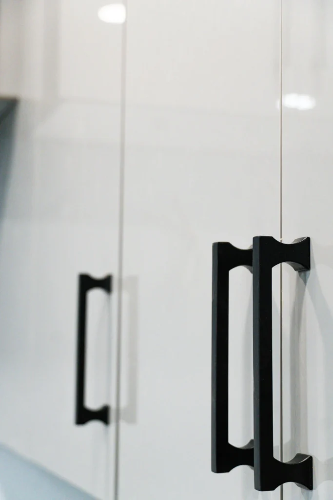 Close-up of matte black bar handles on white cabinet doors