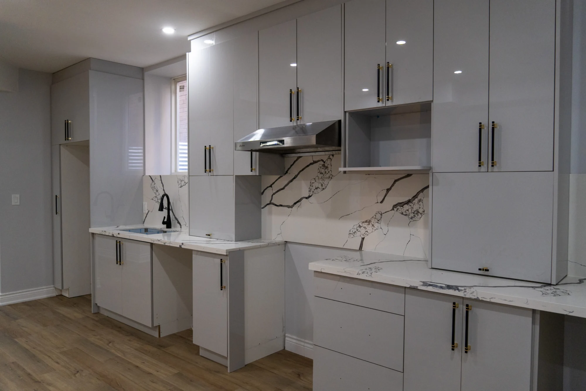 Grey high-gloss custom kitchen with handleless lower cabinets and a stainless hood