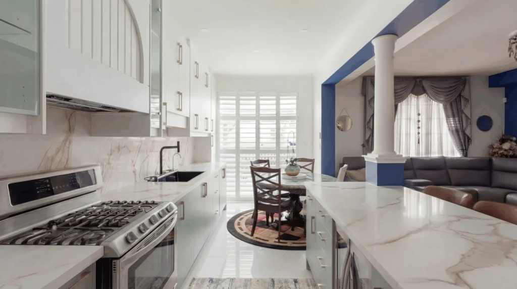 Side view of a white and sage green custom kitchen with a gas range and dining area